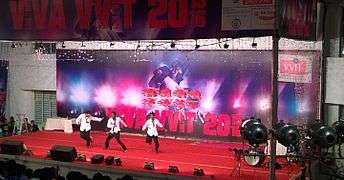 Three male students in white shirts dancing onstage