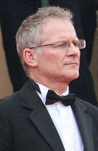 Portrait photo of a man with salt-and-pepper hair and glasses in a tuxedo with a bow tie.