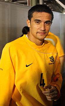 A man with dark hair in a yellow, long-sleeved top.