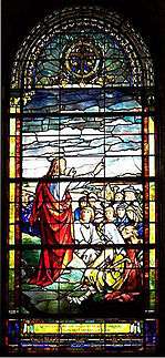 Christ standing on mountain, stretches his arm towards the  people gathered to hear Him speak.