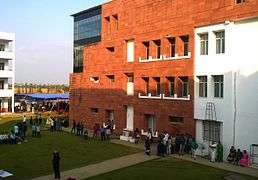 Modern red-brick building, with people standing around it