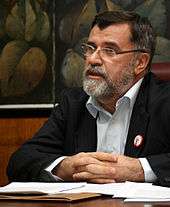 A man with glasses and a graying beard, Veran Matić, sitting at a table