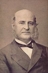 Photograph showing the head and shoulders of an older man with large sideburns and wearing a formal coat and black bow tie