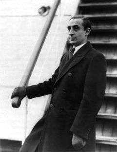 A half-length portrait of Vladimir Horowitz stood by the steps of a boat, facing left. The photo was taken in 1931, when Vladimir Horowitz was in his late twenties. He is wearing a long coat, leather gloves, a white shirt and a tie.