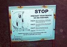 A white warning sign with a picture of the Grim Reaper and the headline "Prevent your death. Go no farther" over black text explaining the dangers to divers of proceeding into the cave without proper equipment and certification