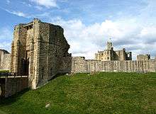 Tall, angular stone building, with lower walls attached on either side