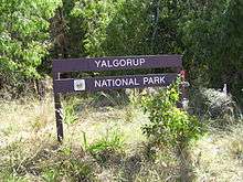 Wooden sign in front of trees and vegetation