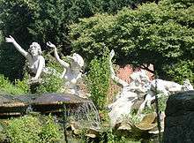 Colour photograph of rockery from the side showing three ladies facing forward and up with their right hands raised