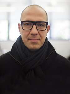 Headshot of a bald man with glasses, smirking at the camera.